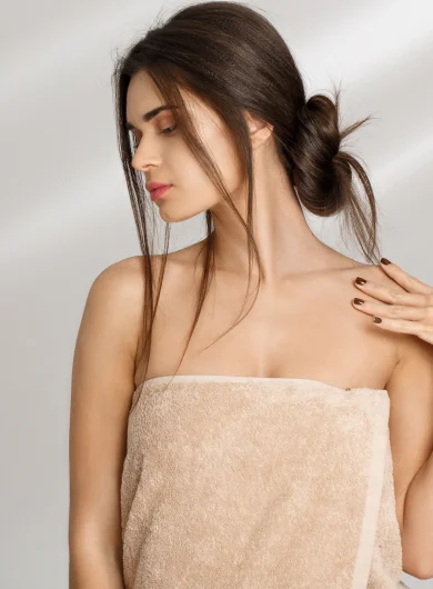 Woman wrapped in towel showing glowing skin after facial treatment at Two Chicks Aesthetics in Port Jefferson NY