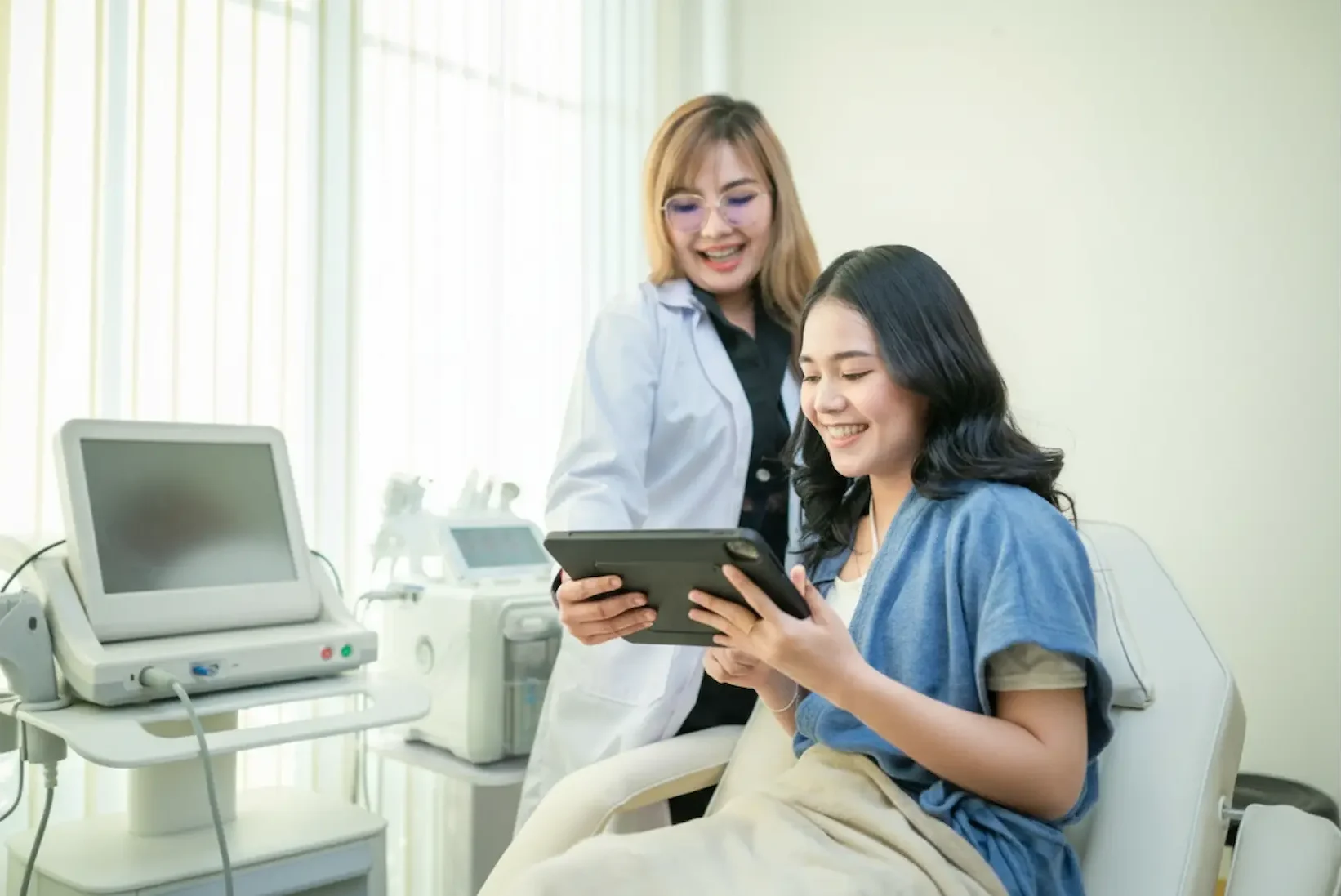 Personalized Botox Service in Port Jefferson — Expert care for natural-looking results 3 A healthcare specialist using a tablet to explain the benefits and expected results of a Botox service to a smiling patient during a consultation.