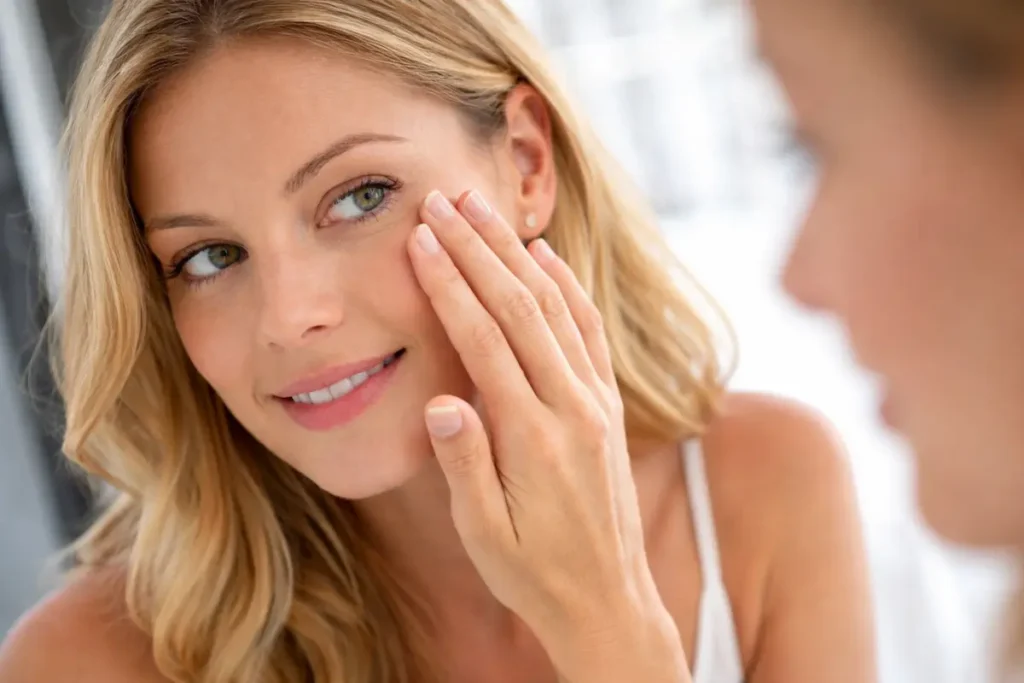 Botox Aftercare: What to Know 8 Woman gently touching under eye area while looking in mirror as part of Botox aftercare skincare routine